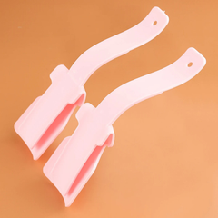 Shoe Helper - Two curved light pink plastic shoe helpers positioned side by side on a solid tan background