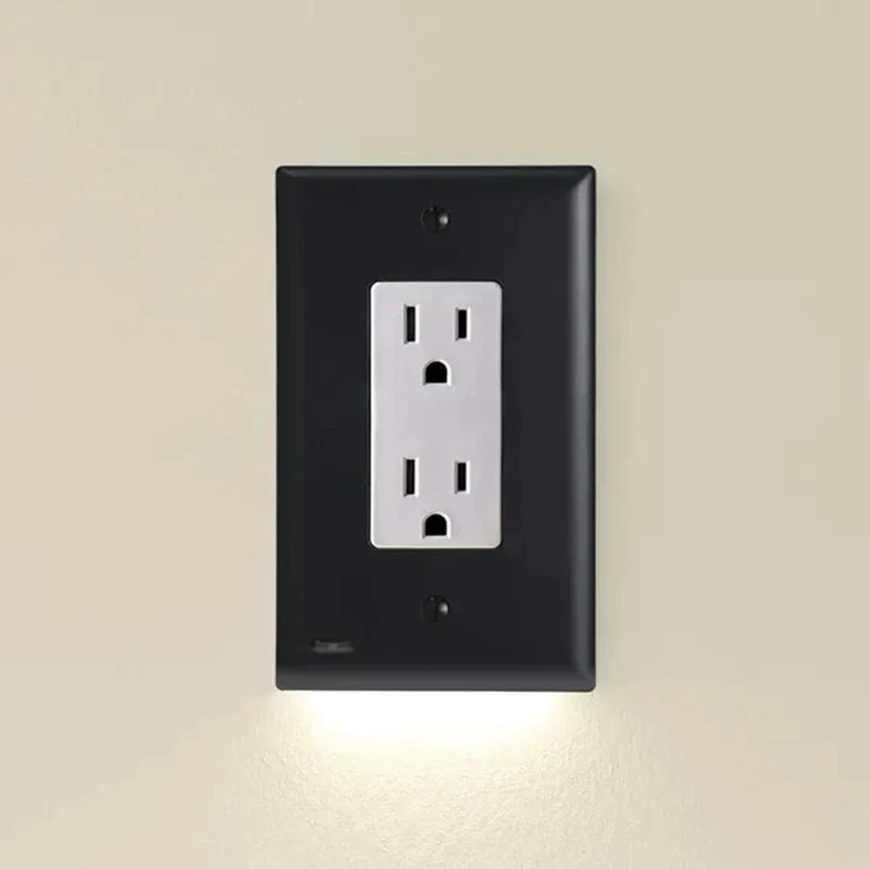 An outlet cover with integrated led night guidelight is mounted on a light beige wall, with soft LED light glowing from its bottom edge.
