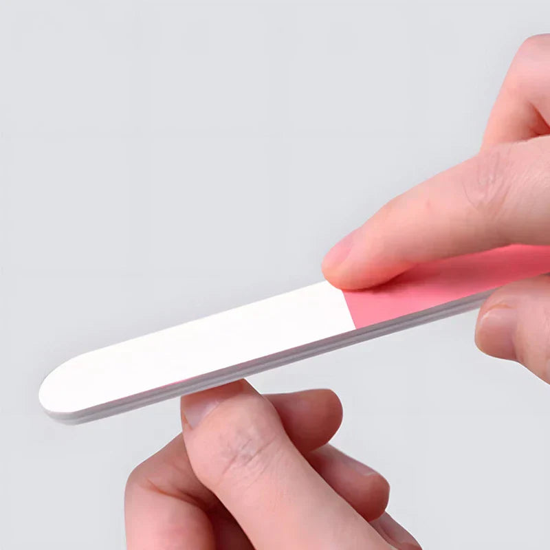Manicure Grooming Kit - Hand holding dual-sided pink and white nail file against plain background