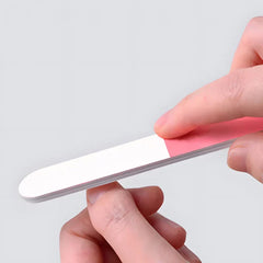 Manicure Grooming Kit - Hand holding dual-sided pink and white nail file against plain background