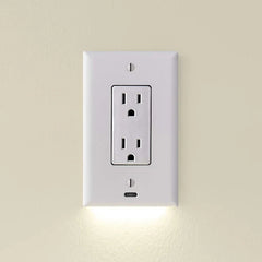 White outlet cover with integrated led night guidelight emits soft downward light, mounted on a beige wall with two electrical sockets.