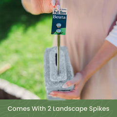 Hand inserting landscape spike into grey stone edging for secure installation