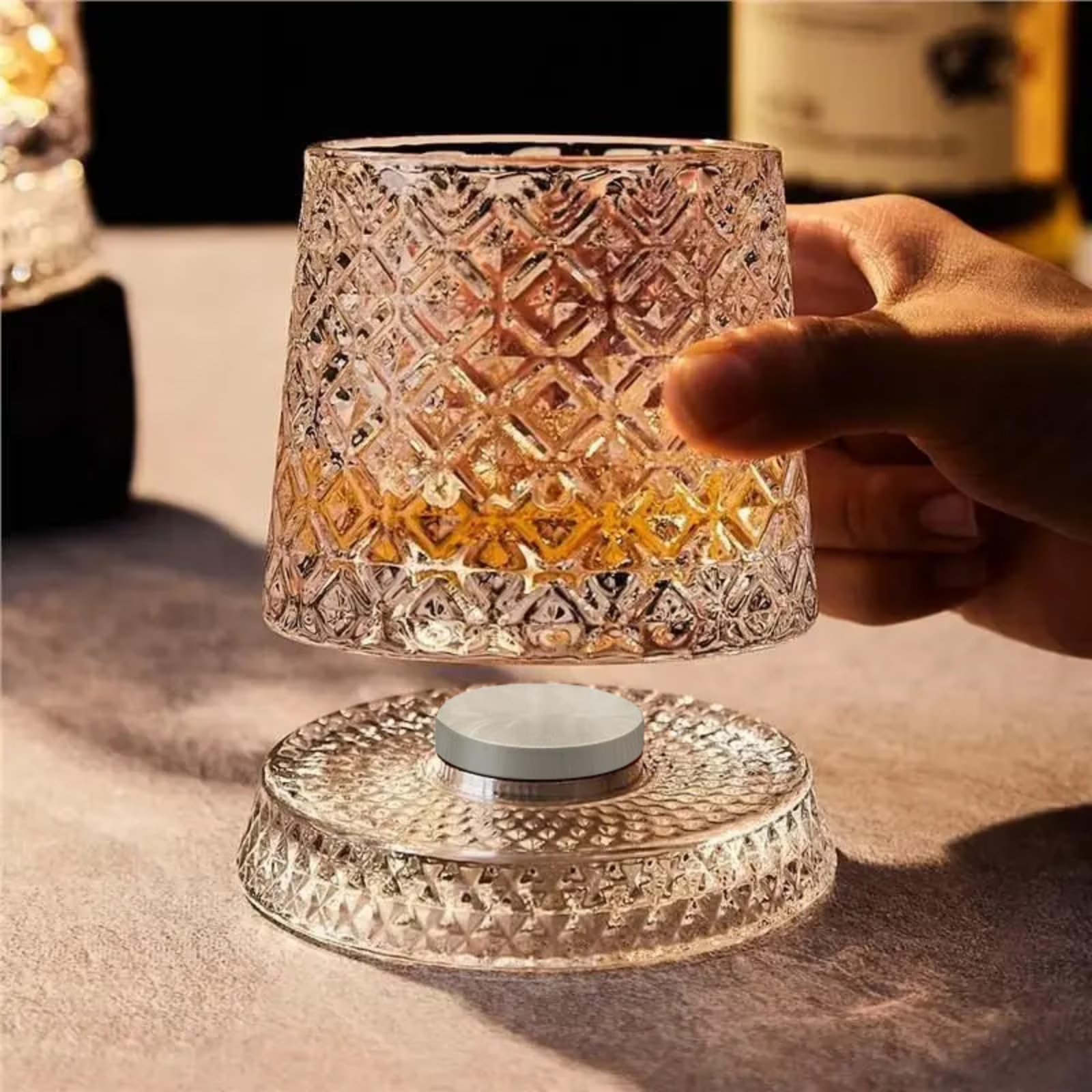 Crystal Whiskey Glass - A hand grips a clear diamond-patterned short glass with amber liquid inside, positioned above its matching glass base.