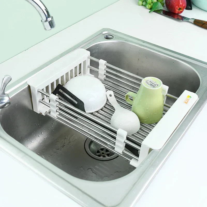 Stainless steel sink with a dish rack holding a bowl, spoon, and cup, with a rolling utility cart not visible in the frame