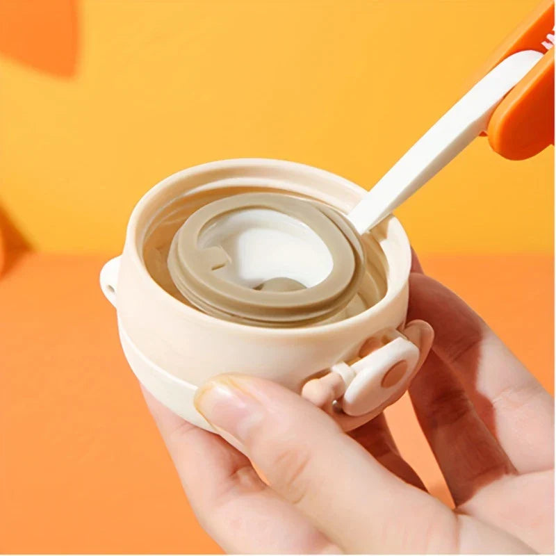 Bottle Cap Cleaning Brush Tool - A hand holds a beige cup lid, with a white and orange cleaning tool's flat tip inserted along the lid's inner edge.