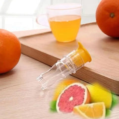 Clear citrus juicer with yellow top on wooden board, next to orange and juice glass