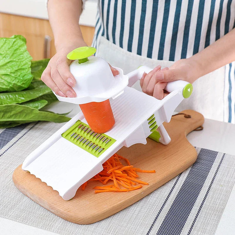 Vegetable Slicer Chopper - Person slicing a carrot into thin strips with a white and green mandoline slicer set on a wooden cutting board