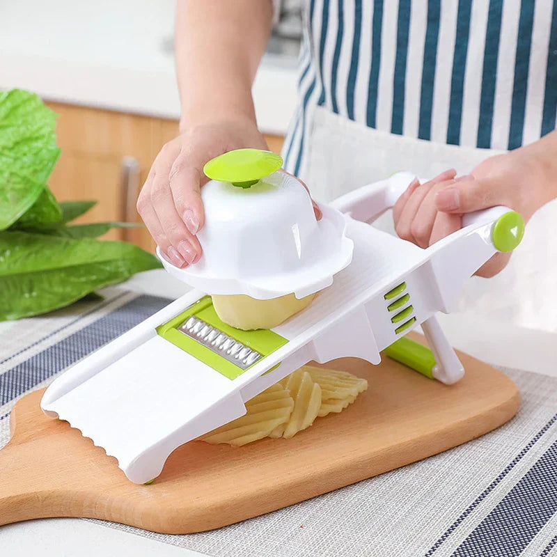 Vegetable Slicer Chopper - Person slicing a potato into wavy slices with a white and green mandoline slicer on a wooden cutting board