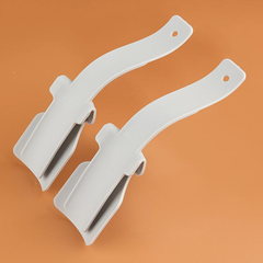 Shoe Helper - Two light gray plastic curved clips resting on an orange surface