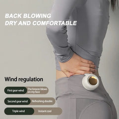 Woman wearing gray outfit with white portable fan clipped to waist for back cooling