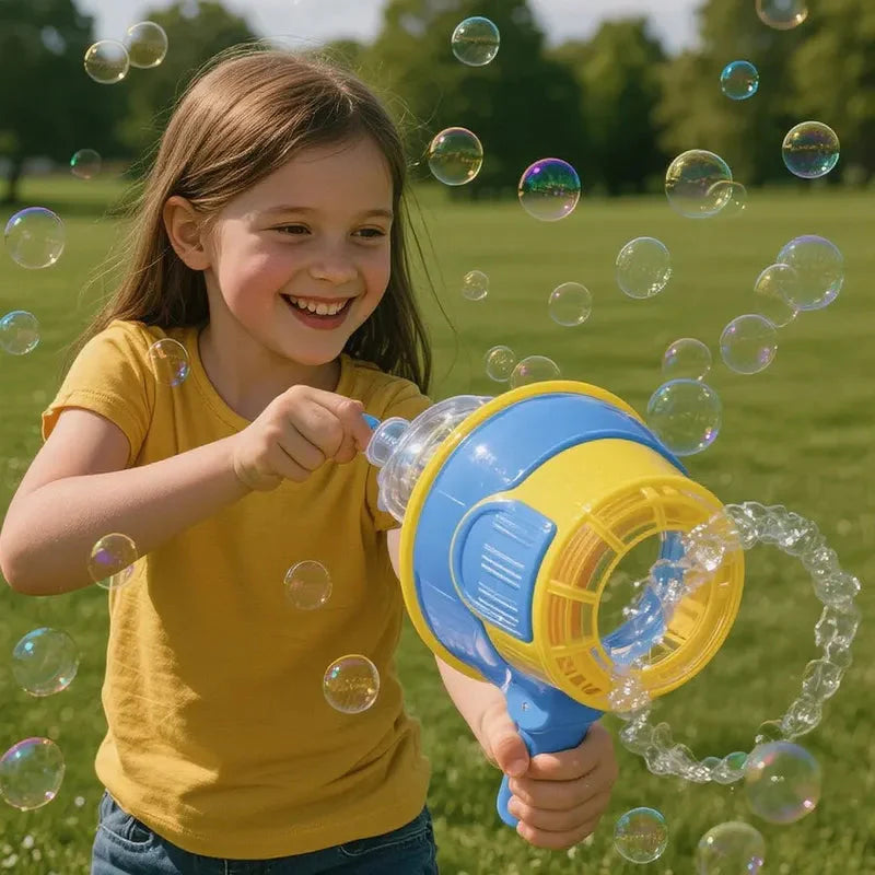 Smiling girl in a yellow shirt holding a blue and yellow bubble gun, with bubbles floating around her on a grassy field.