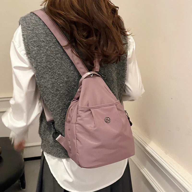 Bolso convertible de hombro: vista trasera de una persona con camisa blanca y chaleco gris llevando un bolso convertible cruzado/mochila color púrpura polvoriento en la espalda