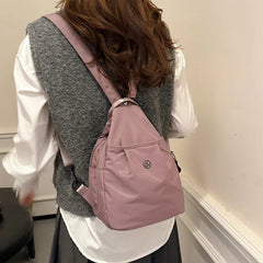 Bolso convertible de hombro: vista trasera de una persona con camisa blanca y chaleco gris llevando un bolso convertible cruzado/mochila color púrpura polvoriento en la espalda