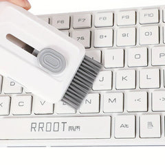 Electronics Cleaning Kit - A hand holds a white cleaning tool with a gray brush, brushing a white computer keyboard.