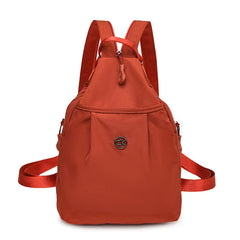 Bolso convertible de hombro: vista frontal de una mochila pequeña color terracota con correas para los hombros, asa superior y insignia central con logotipo