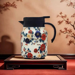 Vintage Floral Tea Thermos - Floral-patterned insulated carafe with black lid and handle resting on a dark wooden inlay tray against a branch-decorated wall