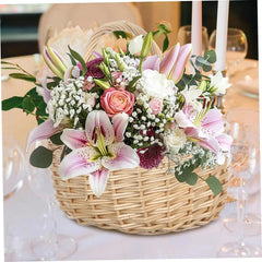 Storage Basket - A wicker flower basket with a mixed floral arrangement rests on a table set with wine glasses and candles.