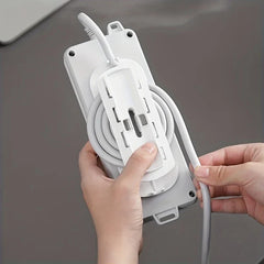 Power Strip Holder - Hands attaching white plastic mount to the back of a power strip with coiled cord