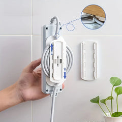 Power Strip Holder - Hand holding a white power strip attached to a wall-mounted white clip, with coiled cable and a separate wall clip shown