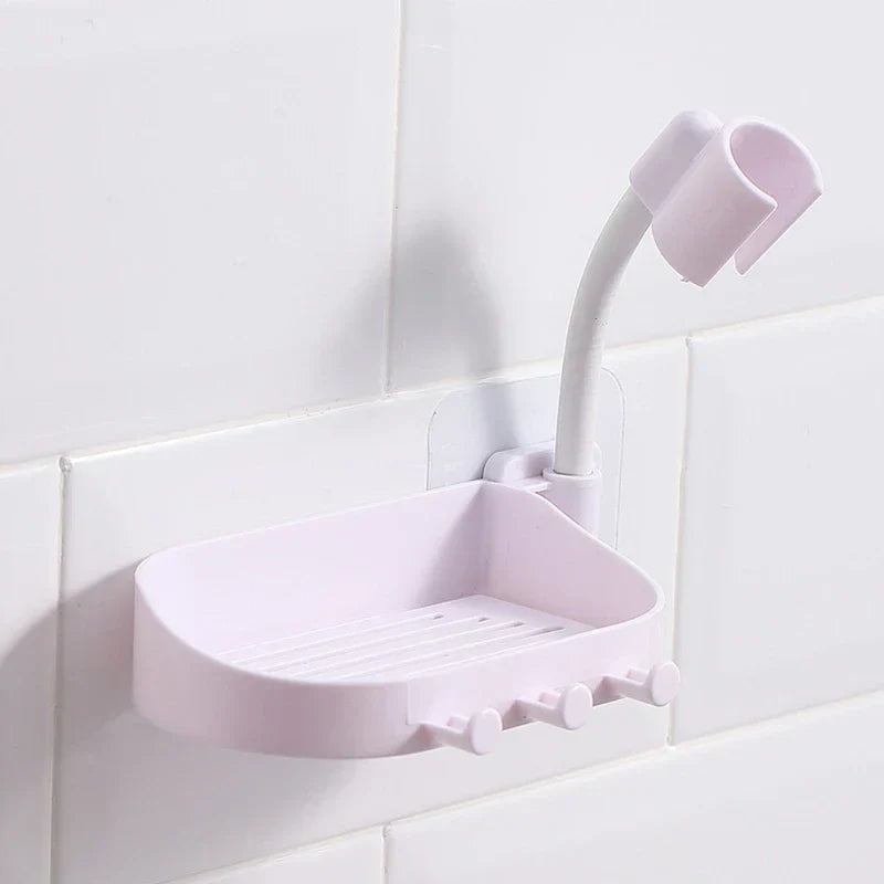 Light pink wall-mounted soap dish with hooks and a flexible shower head holder attached to white tile
