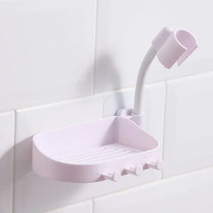Light pink wall-mounted soap dish with hooks and a flexible shower head holder attached to white tile