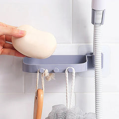 Shower Head Holder - Light gray shower soap caddy mounted on white tile, with a hand holding soap and items hanging from hooks