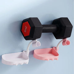 Shower Head Holder - White and pink wall-mounted soap dishes with hooks and curved hose clips hold a 2KG dumbbell on a light blue wall.