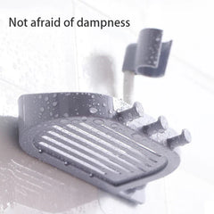 Shower Head Holder - Grey wall-mounted soap dish with hooks and a curved hose clip, covered in water droplets, against a wet tiled surface.
