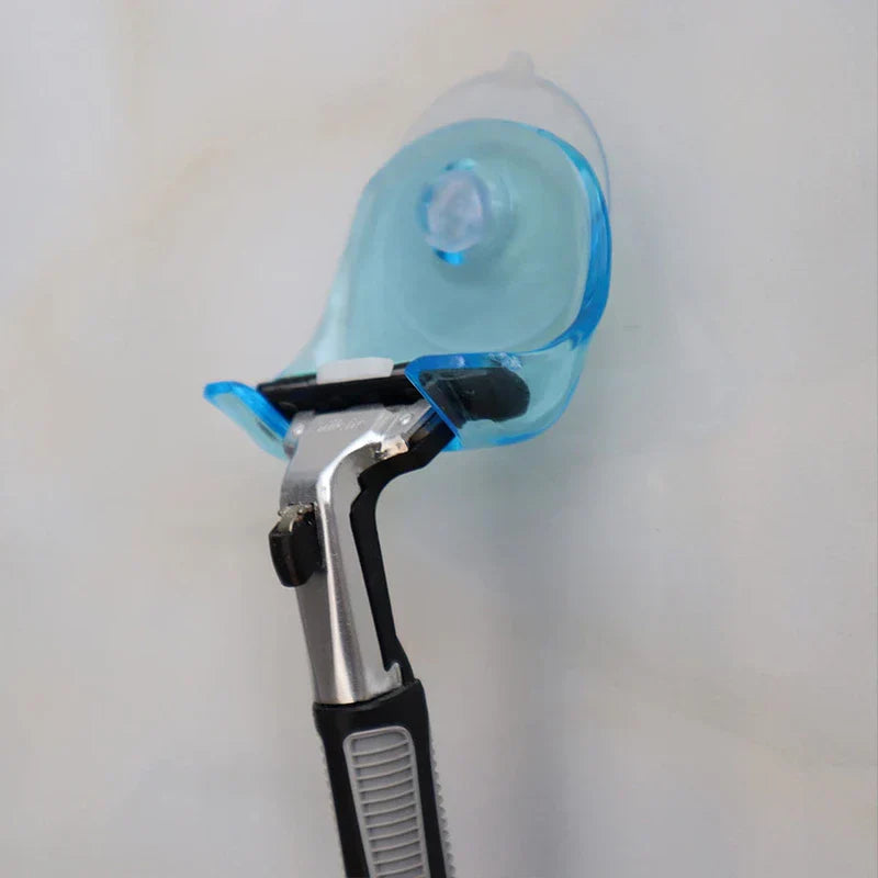 Soporte de pared adhesivo con ventosa para maquinilla de afeitar - un soporte para maquinilla con ventosa azul sostiene una maquinilla manual contra una pared lisa de color claro