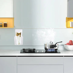 Storage Box - Clear adhesive wall holder mounted on a kitchen backsplash, holding golden utensils, near a stovetop with a pot and tomatoes.
