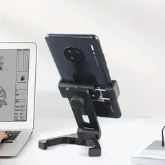 Soporte para teléfono móvil - Soporte ajustable negro sosteniendo un smartphone sobre un escritorio junto a una computadora portátil