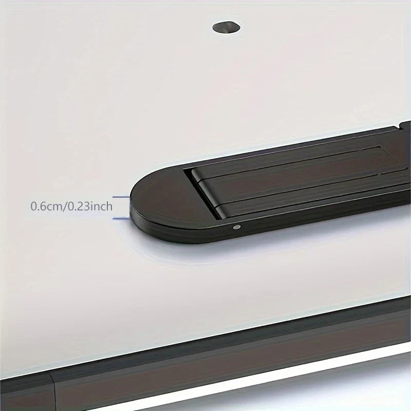 Portable Laptop Stand - Close-up of a thin black rectangular object with rounded ends, measuring 0.6 cm thick, resting on a light-colored smooth surface.