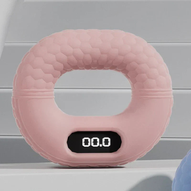 Pink digital hand grip strengthener with 00.0 displayed on its screen, on a light gray shelf.