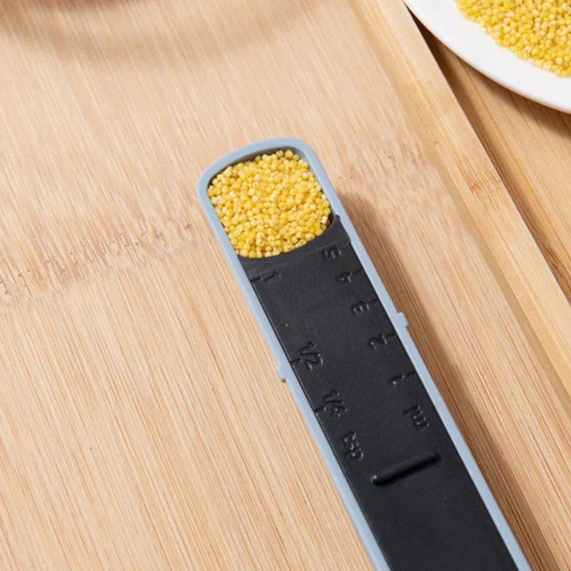 Adjustable measuring spoon holding yellow millet on a wood-grain surface, with a partial white dish of millet nearby