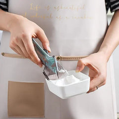 Adjustable Measuring Spoon - A person holds a white container of powder in one hand, using a translucent teal measuring scoop with a lever to release powder into the container.