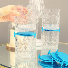 Shelf Organizer Rack - A hand placing a clear cut-glass cup onto another stacked cup with a blue plastic clip; extra blue clips sit on a glass table