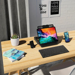 Tablet Desk Mount Stand - Wooden desk with a tablet on a black stand, wireless keyboard, two phone stands, books, and a potted cactus