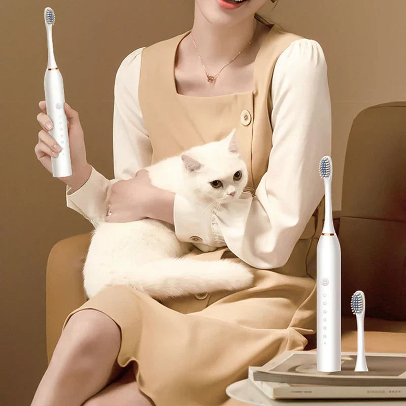 Electric Tooth Cleaning Brush - Person in beige dress holding a white electric toothbrush while holding a white cat, with a second electric toothbrush and spare head on books nearby