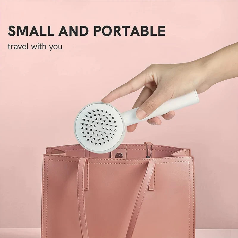 cepillo desenredante para el cabello - mano sosteniendo un cepillo blanco de mano sobre un bolso de piel rosa, texto 'PEQUEÑO Y PORTÁTIL viaja contigo' sobre fondo rosa claro