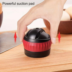Knife Sharpener System - Hand gripping a black and red rounded kitchen tool on a wood counter, with red upward arrows at either side and text reading Powerful suction pad.