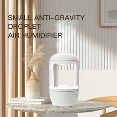 Small anti-gravity droplet air humidifier sits on a marble table, with mist rising and decorative decor in the background.