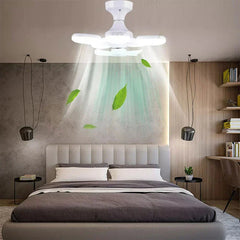 Ceiling-mounted white fan light fixture hangs over a modern bedroom bed, emitting light and airflow shown with floating green leaves.