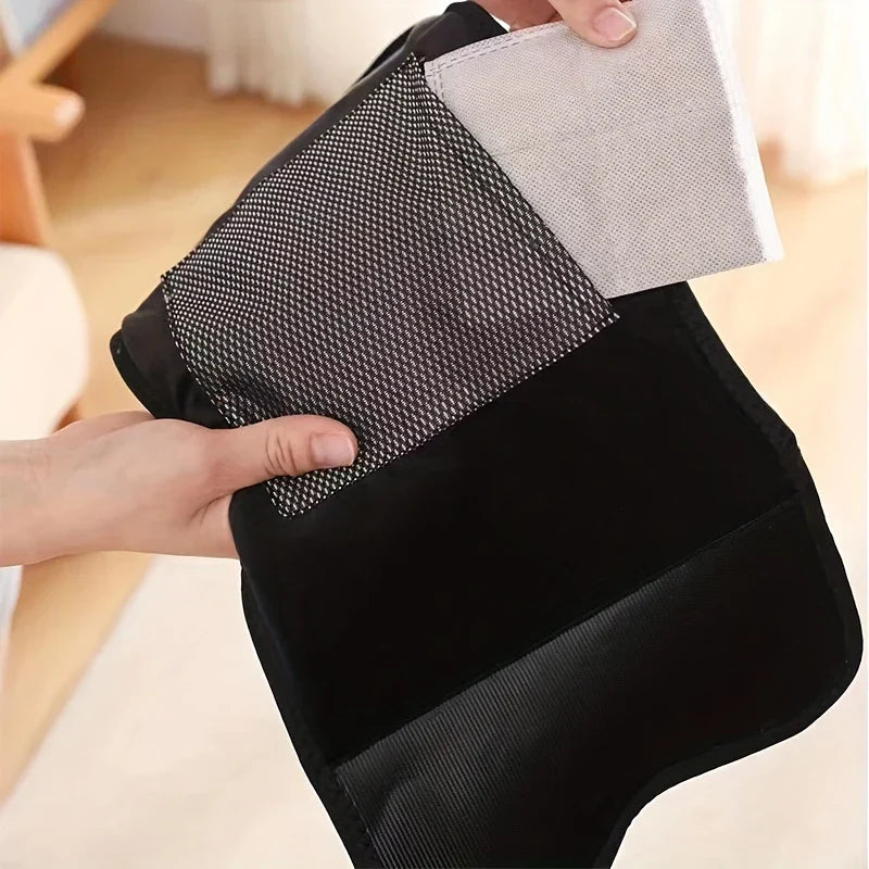 Compression Massager - Hands hold a black fabric wrap showing a mesh panel and light gray fabric insert