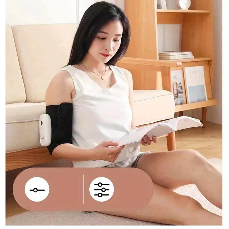 Compression Massager - Woman sits on floor reading a book, wearing a black arm wrap with a white device on her upper arm