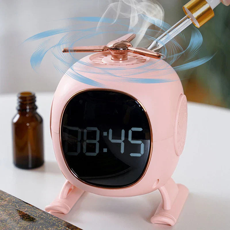 Altavoz bluetooth - reloj rosa con forma de helicóptero al que se le añade niebla, sobre una superficie blanca junto a un pequeño frasco marrón