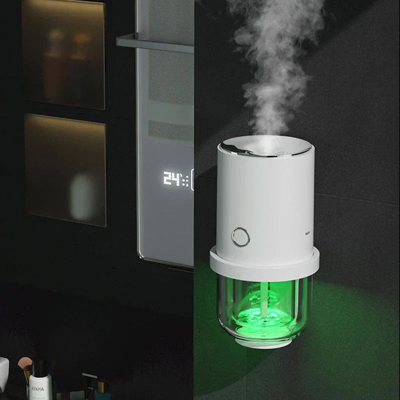 humidificador - difusor que emite niebla fría con luz LED verde, colocado sobre una encimera oscura de baño junto a artículos de cuidado de la piel