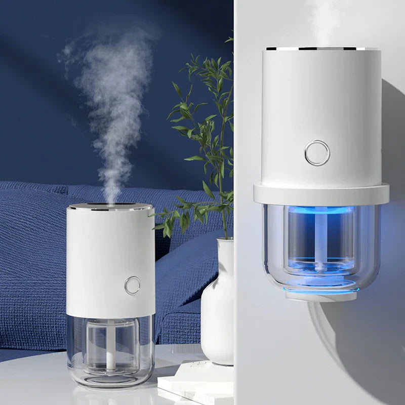 Humidifier - Two white humidifiers with blue LED lights releasing mist; one on a table near a plant and couch, the other mounted on a wall