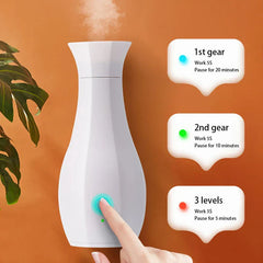 Máquina de perfume - Un dedo presiona el botón de un difusor blanco con forma de jarrón, con tres cuadros de texto que explican tres configuraciones de intervalo de niebla