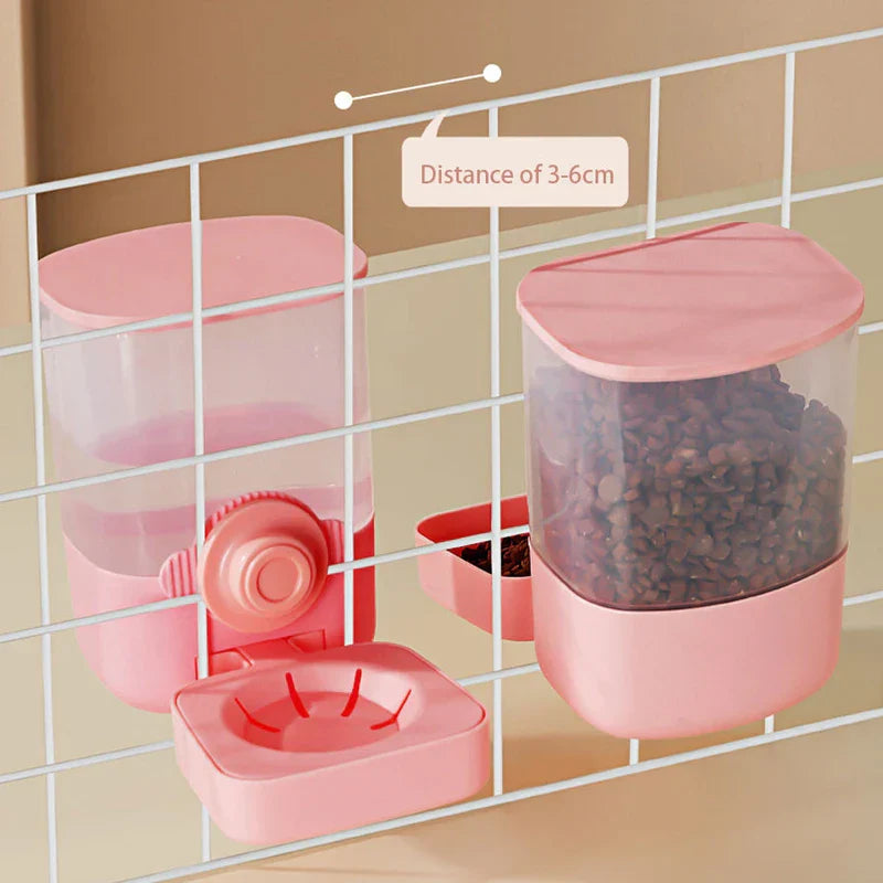 automaattinen lemmikkiruokkija - Kaksi vaaleanpunaista lemmikkiruokkijaa roikkuu valkoisella lankaverkolla; toisessa on nappuloita, toisessa vesikulho, ja 3-6 cm etäisyysmerkintä