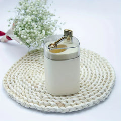 Toothpick Dispenser Holder - Cream and gold unit placed on a woven rattan mat with baby's breath flowers in background
